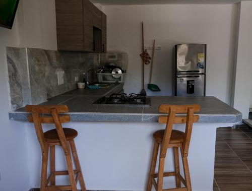 圣安特罗Cabañas en San Antero Bambumar2的厨房在柜台上设有两张木凳