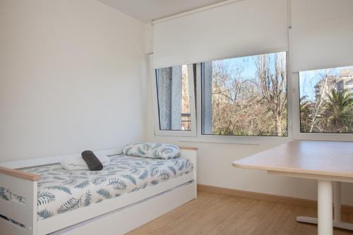 拉雷多Apartamento en Costa de Cantabria, Laredo的一间卧室配有一张带书桌的床和两个窗户。