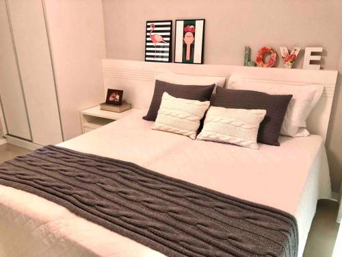 邦比尼亚斯Muito confortável, vista do mar, todo climatizado的卧室配有白色大床和黑白色枕头