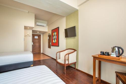 雅加达1O1 URBAN Jakarta Thamrin的酒店客房配有一张床、一把椅子和一张书桌
