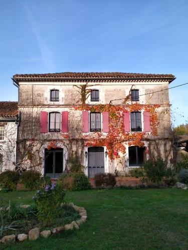 VouzanL'oree du Bois - Chambres independante的一座古老的石头建筑,上面有红色百叶窗