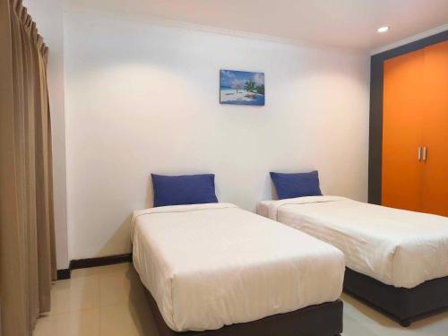 武里南Jt Place Buriram的两张位于酒店客房的床,配有蓝色枕头