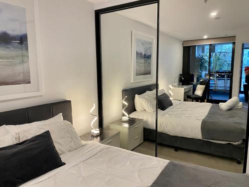 堪培拉Midnight Luxe 1 BR Executive Apartment L1 in the heart of Braddon Pool Sauna Secure Parking Wine WiFi的一间卧室配有两张床和镜子