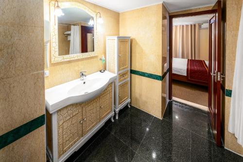 河内EDEN HOTEL HÀ NỘI的一间带水槽和镜子的浴室以及一张床