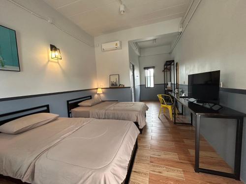 北碧บ้านสุขซอย5的酒店客房设有两张床、一张桌子和一台电视。