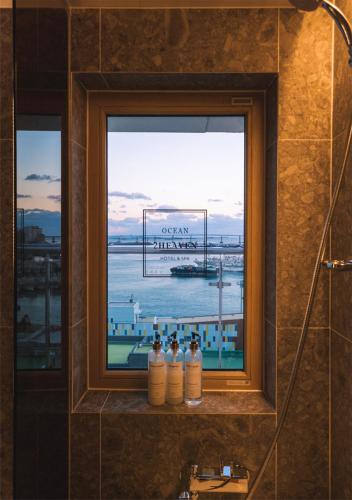 釜山Nampo Ocean2Heaven Hotel& Spa的浴室窗户,在窗台上放有四瓶