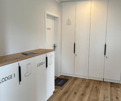 于斯德Dünen Lodge 3的厨房铺有木地板,配有白色橱柜。