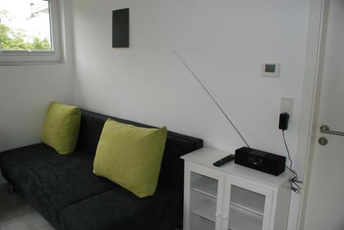 于斯德Strandhaus Rose Apartement 14的一张黑色沙发,配有黄色枕头和收音机