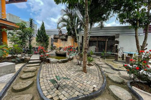Kedemangan-wetanSalsabila Villa Syariah RedPartner的一座花园,在一座建筑前种有树木和花卉