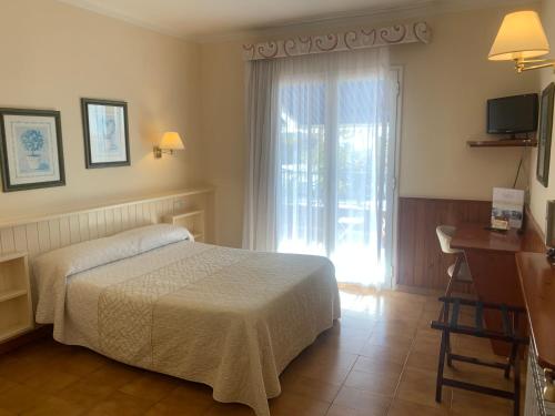 圣苏珊娜Casa feliu的一间卧室配有一张床、一张书桌和一个窗户。