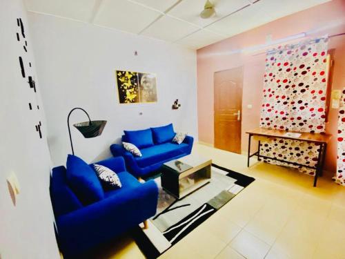 瓦加杜古Sawadogo meublée的客厅设有2张蓝色的沙发和1面墙