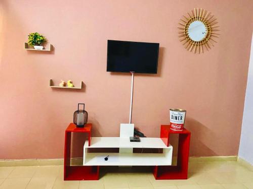 瓦加杜古Sawadogo meublée的客厅设有粉红色墙壁上的电视