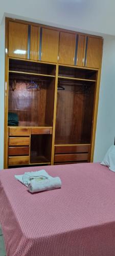 维拉维尔哈SUÍTE Alfa的一张带粉色毯子和木制衣柜的床