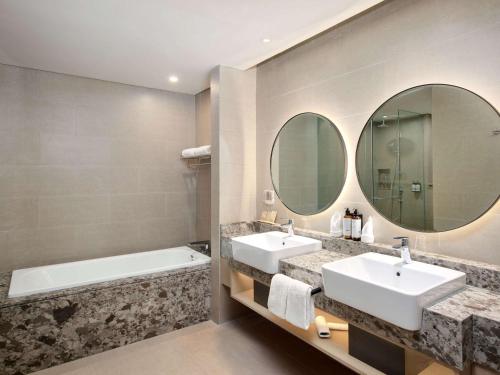 明古鲁省Mercure Bengkulu的浴室配有2个盥洗盆、浴缸和镜子