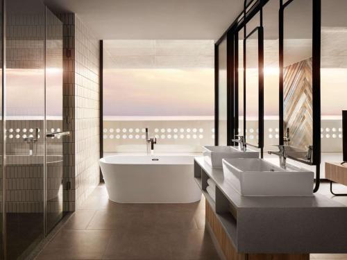 西哈努克Novotel Sihanoukville Holiday Resort的浴室配有两个盥洗盆和浴缸。