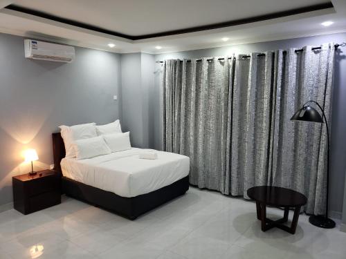 奇帕塔The KWASU Apartments的一间卧室配有一张床、一张桌子和窗帘