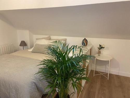 蓬图瓦兹La Mansarde LCD Pontoise的一间卧室配有一张床和一张植物桌子