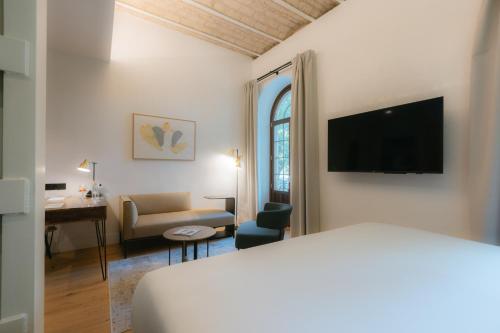 塞维利亚Cavalta Boutique Hotel GL的酒店客房配有一张床、一张书桌和一台电视。