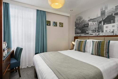 伦敦Seraphine Hammersmith Hotel的配有一张床、一张书桌和一扇窗户的酒店客房