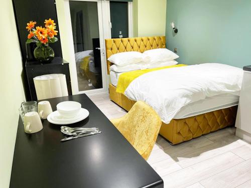 PinnerLetzi Private En-Suite In Harrow的一间卧室配有床和一张桌子,上面有盘子