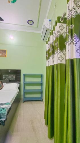 AyodhyaPrakash Homestay的一间设有床铺和绿帘的房间