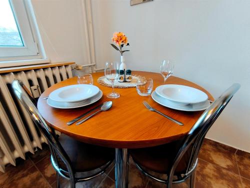 尼特拉Apartmán Green的一张木桌,上面放有盘子和酒杯