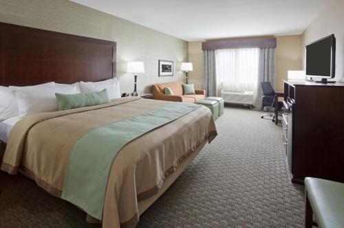 MorrisGrandStay Hotel & Suites - Morris的酒店客房设有一张大床和一台电视。