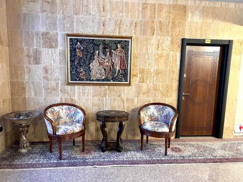 PernikХотел Антик的三把椅子和一张桌子,墙上有一幅画