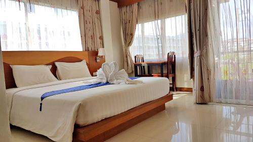 芭东海滩绿色海港酒店 & 服务公寓的卧室配有一张带白色床单和窗户的大床。