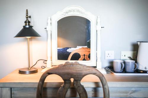 斯通豪斯The Lazy Goose - Coffee House & Bedrooms的一张木制桌子,镜子前配有椅子