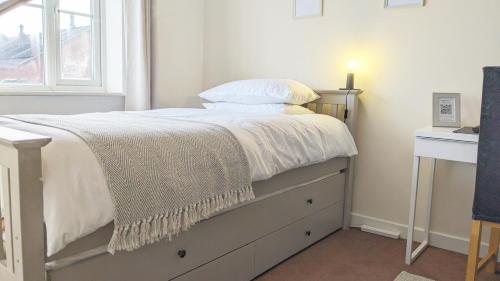 朗伊顿Spacious Room with Parking TV Wi-Fi Desk Kettle的一间卧室配有一张带白色床单的床和一扇窗户。
