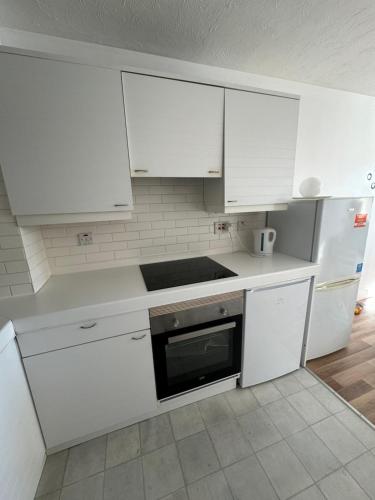 伦敦Perfect in the centre with view的白色的厨房配有白色橱柜和炉灶。