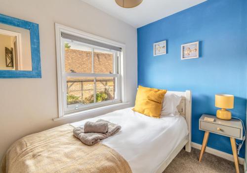 Titchfield2 BR Stylish Bright Cottage, Pet Friendly - Titchfield Village by Blue Puffin Stays的蓝色的卧室设有床和窗户