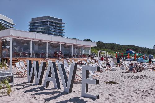米兹多洛杰Wave De Luxe Studio Resort&SPA 755B - Sea View的海滩上的标志,带椅子和建筑