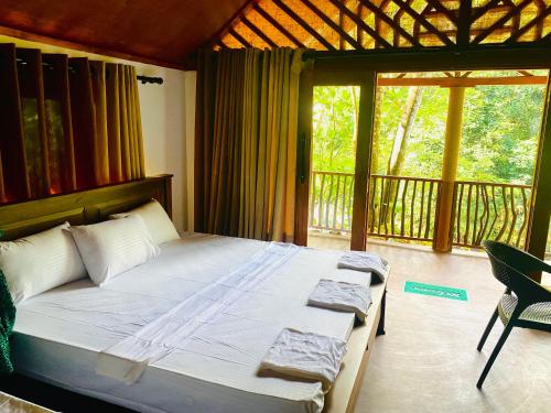 代尼耶耶The Rainforest Hideaway的一间带大床的卧室和一个阳台