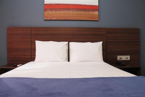 乌贝兰迪亚Days inn by Wyndham Uberlândia的一张铺有白色床单的床和木制床头板