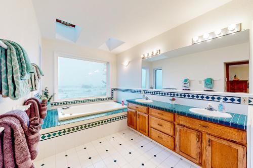 新奥尔良市Pebble Beach Bliss的一间带两个盥洗盆、浴缸和窗户的浴室