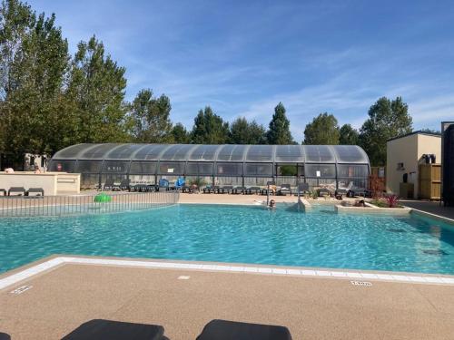 乌伊斯特勒昂Mobil-home Ouistreham的一座大型游泳池,其建筑背景为: