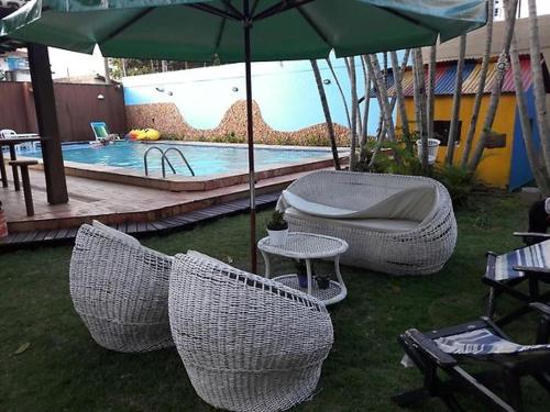 瓜拉派瑞Espaço Hale Kai的一组椅子和一把遮阳伞,位于游泳池旁