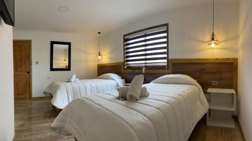 利纳雷斯维多利亚塞德酒店的客房设有三张床、白色床单和窗户。