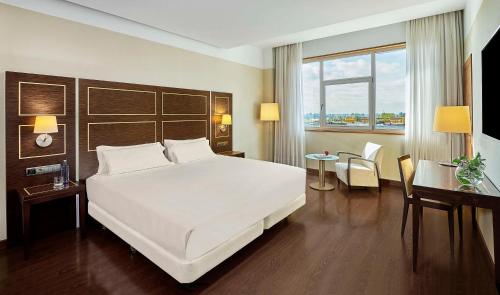 巴达霍斯NH埃斯特雷马杜拉赌场大酒店的卧室配有一张白色大床和一张书桌