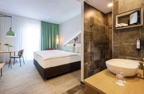 德累斯顿ARCOTEL HafenCity Dresden的酒店客房设有带床和水槽的浴室