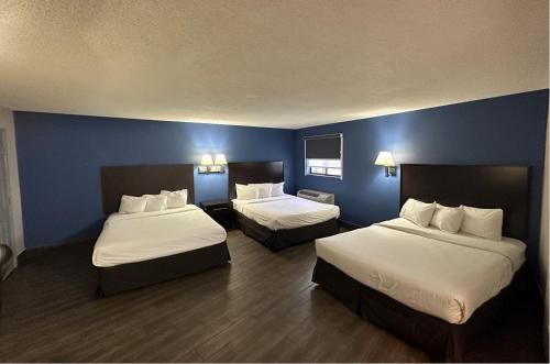 金曼Baymont by Wyndham Kingman的两张位于酒店客房的床,拥有蓝色的墙壁
