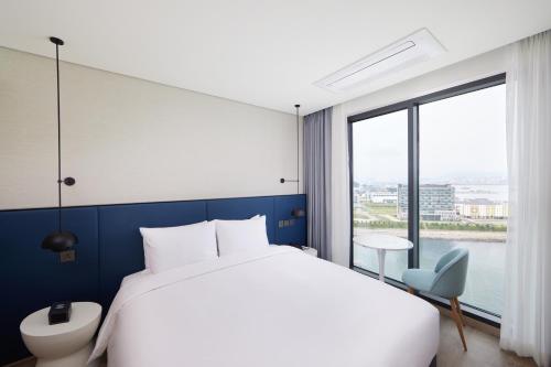 釜山Citadines Connect Hari Busan的一间卧室设有一张大床和一个大窗户