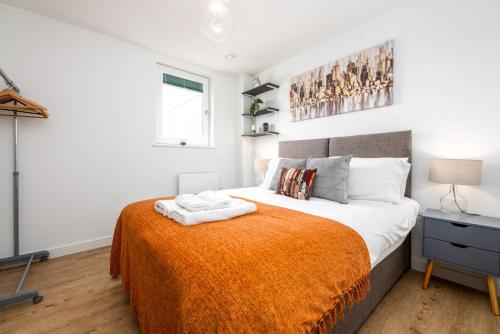 卡迪夫2-bedroom Cardiff Bay apartment Wi-Fi, Parking的一间卧室配有一张带橙色毯子的大床