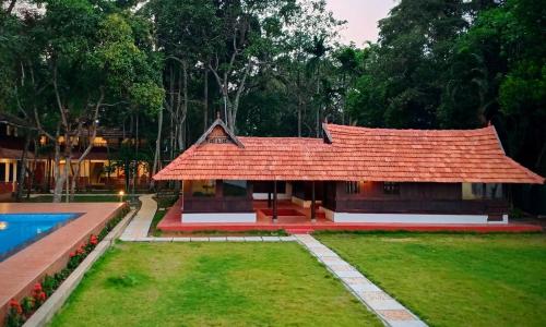 阿勒皮Shantitheeram Ayurveda Lakeside Heritage Resort的一座红色屋顶的房子和一个游泳池