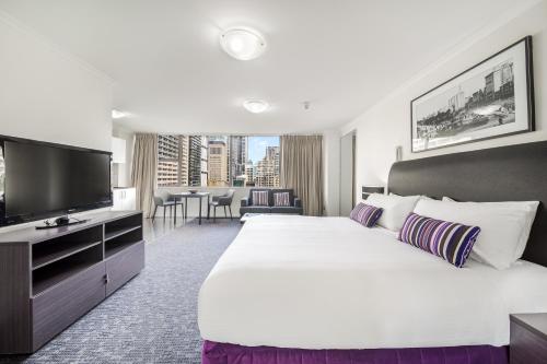 悉尼Oaks Sydney Hyde Park Suites的一间酒店客房,配有一张大床和一台平面电视