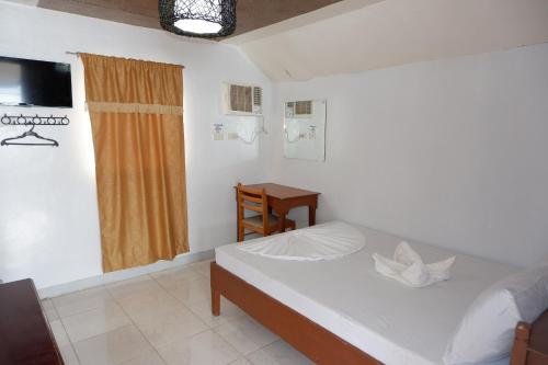 BalateroBuena Lynne's Resort的一间卧室配有一张床、一张桌子和一个窗户。
