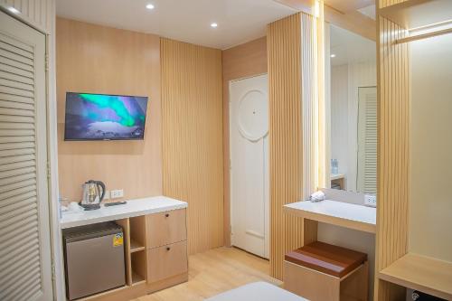 曼谷Thrive Hotel的一间带水槽的浴室和墙上的电视