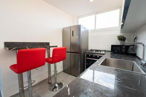 巴特亚姆Beautiful apartment near Tel Aviv的厨房配有红色椅子和不锈钢水槽